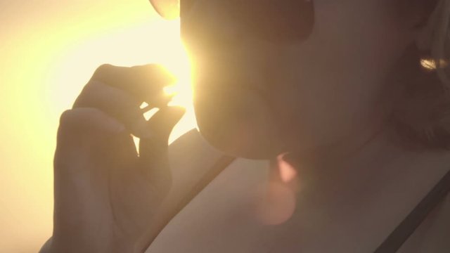 Portrait of a busty girl sucking a lollipop. Backlight, sun flare. Slow motion