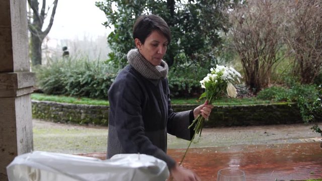 A florist preparing flowers for the wedding catering on a rainy day in Italy, 4K