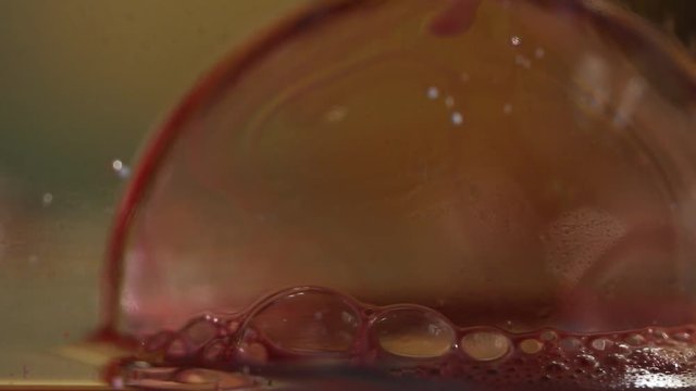 Macro close up, red bubble floats on water