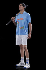 Full length of young male hockey player with stick standing against black background