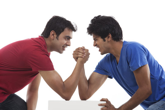 Two young man competing in arm wrestling over white background 