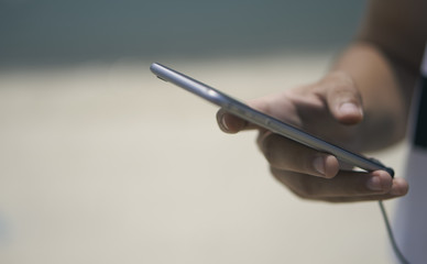 Close-up of a man holding a phone in his hands on the beach