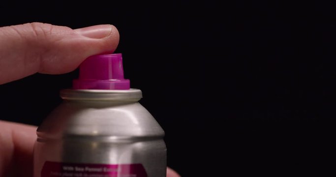 Close up, person sprays hairspray from can in slow motion
