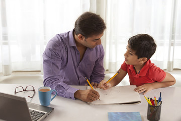 Father helping son with homework at desk