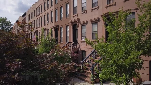 rising over trees to reveal block of Brownstones in Brooklyn