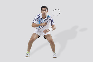Full length of young man playing badminton isolated over white background