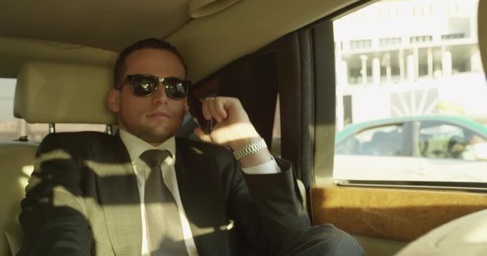 Businessman talks on phone in limo, slow motion
