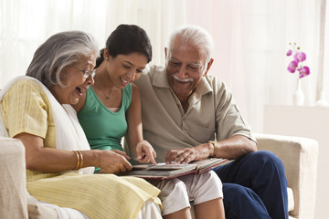 Obraz premium Granddaughter looking at a photo album with her grandparents