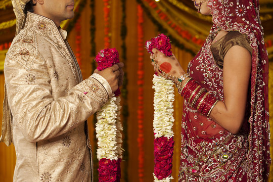 Indian bride and groom holding garlands 