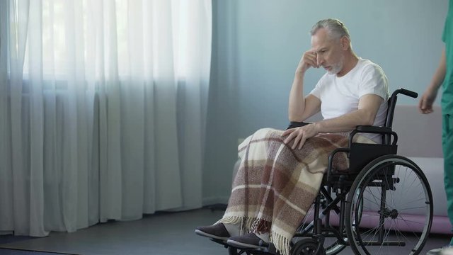 Man with disabilities smiling, feeling support of rehabilitation center worker
