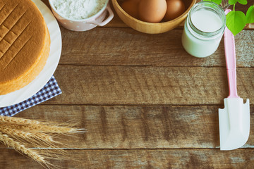 Homemade sponge cake on plate.Soft and lite delicious sponge cake with ingredients: eggs flour milk on wood table.Homemade cake with ingredients with copy space for homemade bakery background concept.