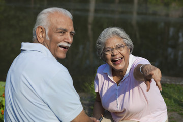 Cheerful couple enjoying at park , woman pointing at something 