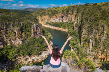 Freedom traveler woman with raised arms on the top of Furnas Canyon enjoying the beautiful landscape. Concept of travel and freedom. Capitolio, Minas Gerais, Brazil.