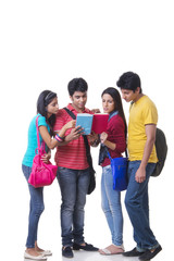 Obraz premium Full length of college friends reading book against white background