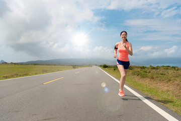 beautiful female athlete running on asphalt road