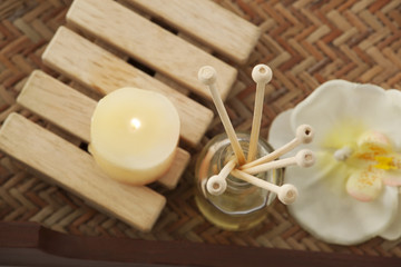 Close-up of reed diffuser with candle and orchid 