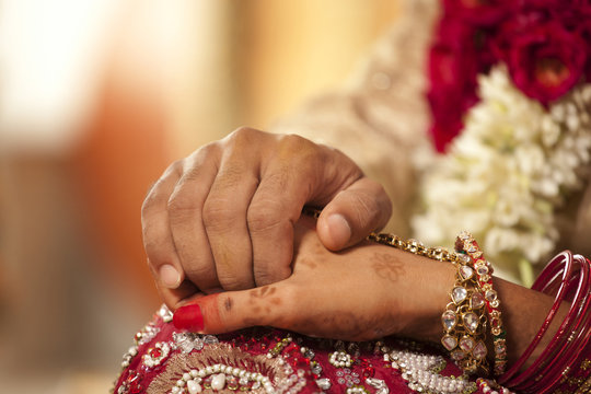 Close-up of groom holding brides hand 