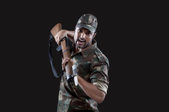 Angry young soldier holding gun 
