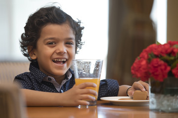 Close-Up of smiling boy with glass of juice on table