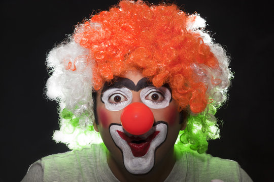 Surprised male clown over black background 