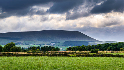 Obraz premium Distance view from farm on Pendle Hill on cloudy summer afternoon