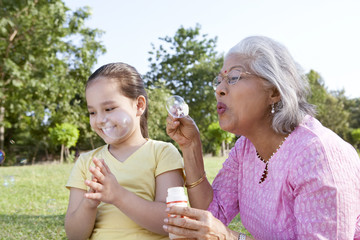 Fototapeta premium Grandmother blowing bubbles for granddaughter