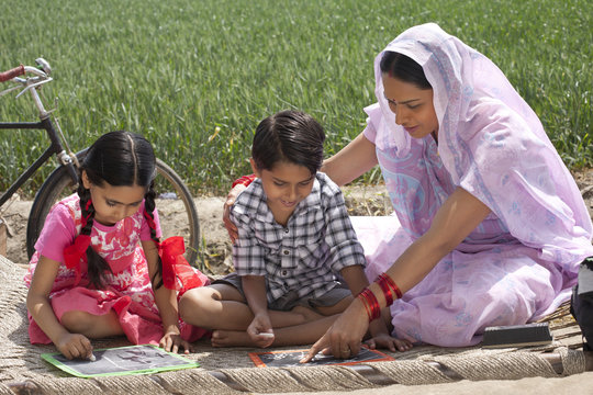 Mother helping daughter and son with their homework 
