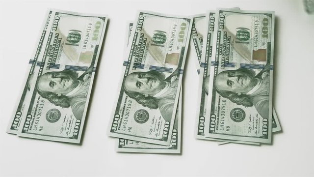 Splitting money into three equal stacks. Men's hand puts hundred-dollar bills on the table, and then takes them away. Fast motion.