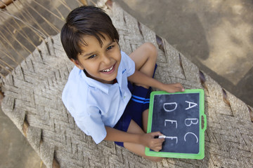 Portrait of a little school boy writing on slate 