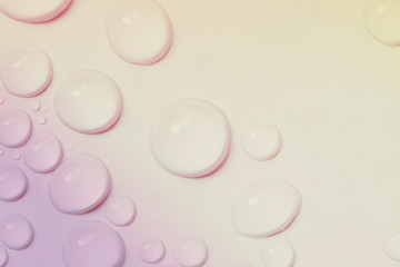 Big and small water drops on yellow-pink background. Closeup. Toned