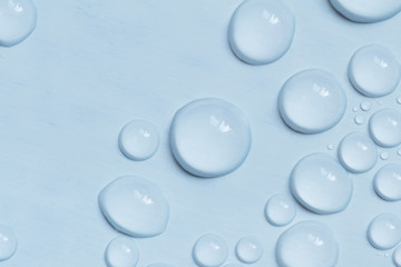 Big and small water drops on blue background. Closeup.
