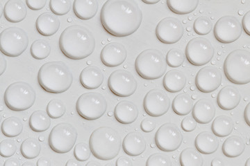 Big and small water drops on gray background. Closeup.