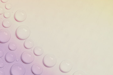 Big and small water drops on yellow-pink background with copy space. Closeup. Toned