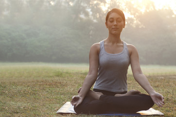 Fototapeta na wymiar Young woman meditating in park 