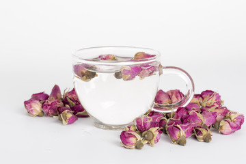 A cup of rose tea with dried rose flower on white background.