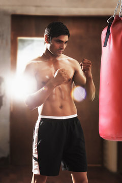 Young shirtless man training on a punch bag