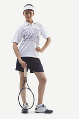 Portrait of young woman with hand on hip holding tennis racket isolated over white background