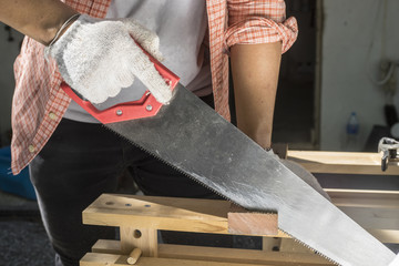 Carpenter holding a hand saw on the work bench