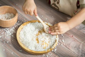 Child helping on the kitchen. Playing with the food. Small hands