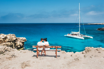 Ein Paar sitzt auf einer Bank und schaut auf die Lagune. Flitterwochen-Liebhaber. Mann und Frau auf der Insel. Verliebtes Paar im Urlaub. Ein Gutschein für eine Kreuzfahrt. Meerestour. Flitterwochen. Hochzeitsreise