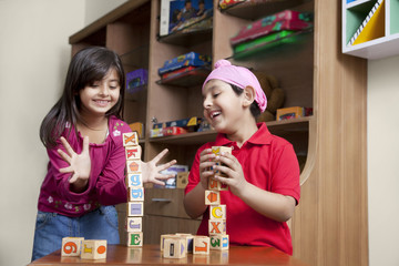 Cute little brother and sister playing with wooden toy blocks 