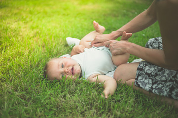 Mother changing diaper of baby in nature