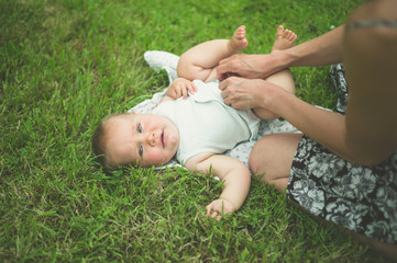 Mother changing diaper of baby in nature