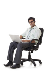 Happy young businessman on chair using laptop 