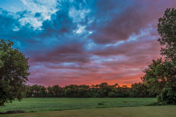 Obraz premium Firey Evening Sunset with Clouds Over Farm Field