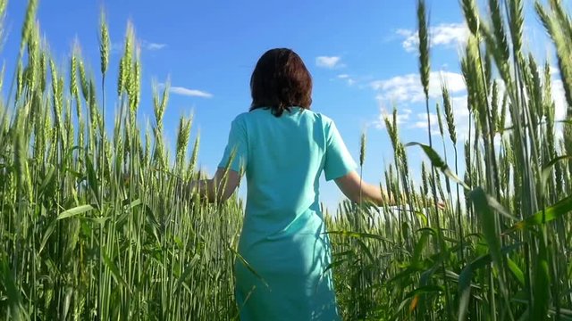 Beauty girl runs on a wheat field over a cloudy sky.