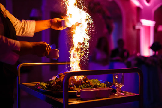 Chef, pouring alcohol into a frying pan with fire