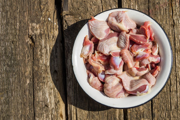 Raw chicken gizzards in metal enamelled bowl on rustic wooden table