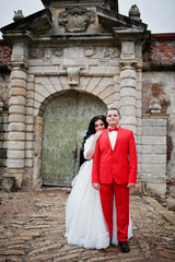 Fototapeta na wymiar Stunning wedding couple posing next to the ancient doors of a castle.