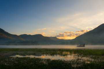 Morning mist floating house in Kanchanaburi, Thailand, the sky is bright colors from sunrise.
